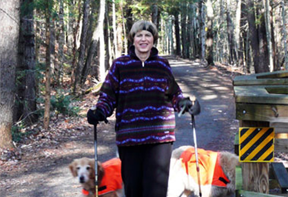 Woman running on snow with dogs wearing icespikes