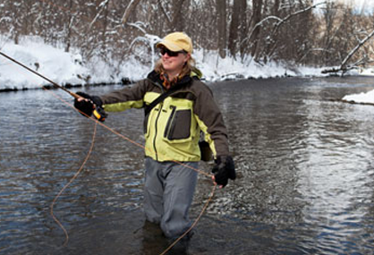 fisherwoman using icespikes for traction in the river